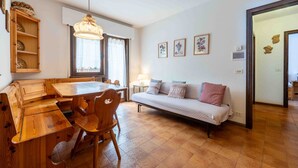 Een gezellige woonkamer met een houten eettafel, een bank en een kroonluchter.