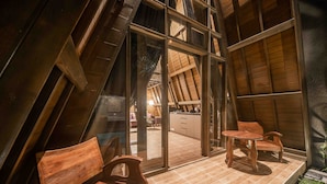 Un espacio interior con techo inclinado, mobiliario de madera y vista hacia una zona de cocina.