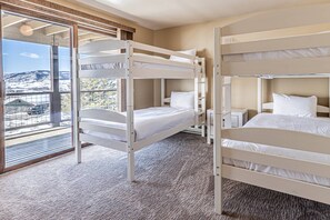 A room with bunk beds, a large window with a view of a snowy landscape, and a carpeted floor.