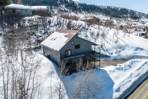 Una casa moderna con tetto spiovente, un balcone e vista su un paesaggio montano innevato.