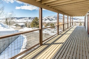 Ein überdachter Balkon mit Blick auf schneebedeckte Berge und eine Stadt.