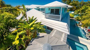 A modern house with a pool, surrounded by tropical vegetation. - Poseidon's Paradise: Luxury Waterfront Rental in Key West, Stunning Backyard Oasis and Private Pool! (Key West)