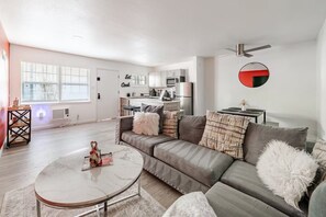 Ein modernes Wohnzimmer mit einer Couch, einem Couchtisch und einer Küche im Hintergrund.