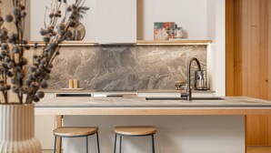 Una cocina moderna con salpicadero de mármol, encimera de madera y dos taburetes.