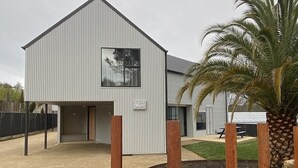 Un edificio moderno de dos pisos con un ventanal grande y una placa con el nombre.