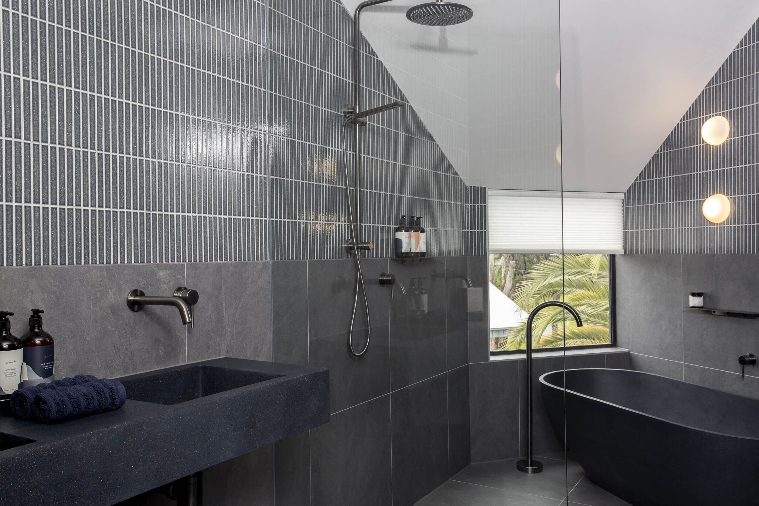 A modern bathroom with a freestanding bathtub, a shower area, and a sink with toiletries.