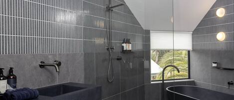A modern bathroom with a freestanding bathtub, a shower area, and a sink with toiletries.