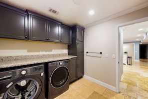 Laundry room with a modern design, featuring a washing machine and granite countertop.