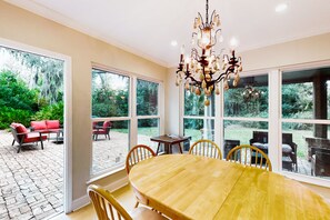 Enjoy family meals and gatherings in this inviting dining area with a large table and comfortable chairs, offering a view of the lush garden.