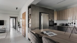 Una cocina moderna con horno empotrado, microondas y cafetera. Hay una mesa de comedor con sillas y un libro encima.