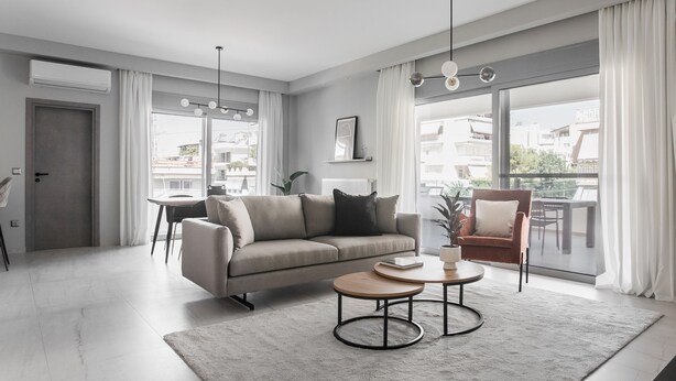 Una sala moderna con sofá, mesa de centro y una butaca. Hay una mesa de comedor con sillas, un ventanal con cortinas y una puerta.