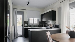 Una cocina moderna con una isla central, armarios negros y un comedor con una mesa redonda y sillas.