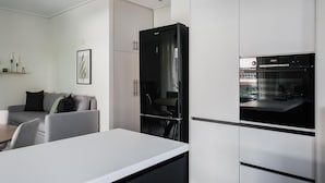 Una cocina moderna con un refrigerador negro, gabinetes blancos y un horno Bosch.