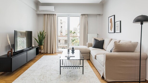 A modern living room with a sofa, a coffee table, and a TV on a black stand.