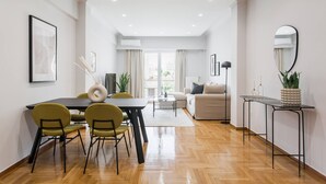 A modern living room with a dining area, featuring a wooden floor, a sofa, a coffee table, and a dining table with chairs.