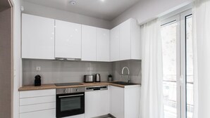 A modern kitchen with white cabinets, a built-in oven, a dishwasher, and a sink.