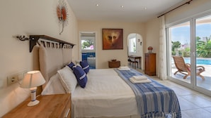 Ein Schlafzimmer mit Bett, Schreibtisch, Stuhl und Blick auf einen Swimmingpool.