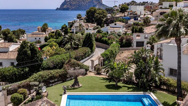 Ein Wohngebiet mit einem Schwimmbecken, umgeben von Grünflächen und Gebäuden im mediterranen Stil.