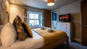 Hotellihuone, jossa on sänky, televisio, jossa näkyy Netflix, ikkuna verhoineen ja ovi.