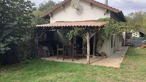 Een huis met pannendak, een overdekte patio en een kleine tuin.