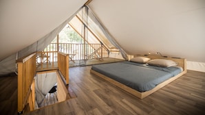Un dormitorio con cama de madera, un balcón pequeño y una escalera de madera.