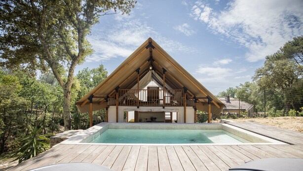 Una terraza de madera con piscina, un área exterior cubierta y vista a una casa con techo inclinado.