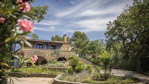 Una casa de piedra con jardín y una escalera que lleva a una terraza.
