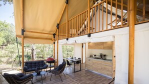 Un espacio al aire libre techado con cubierta de madera, mesa de comedor con sillas, parrilla y zona de cocina con armarios y pileta.