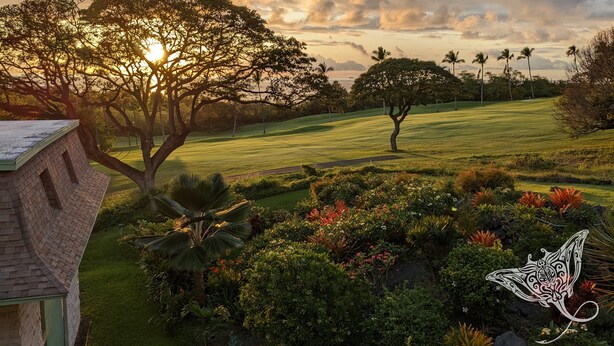 Un jardin aménagé avec une grande variété de plantes et d’arbres, un terrain de golf en arrière-plan et un bâtiment doté d’un toit en pente.