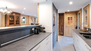 Een moderne keuken met een centraal eiland, inbouwapparatuur en houten kastjes.