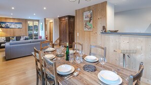 Een eetruimte met een houten tafel voor vier personen, omringd door stoelen. Er is een houten kast en een schilderij aan de muur.