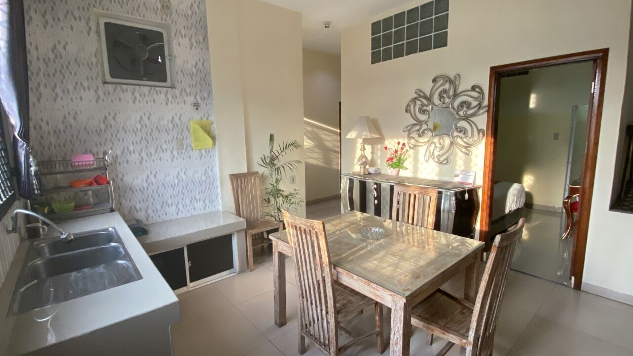 A kitchen with a dining table and chairs, a sink, and a decorative wall piece.