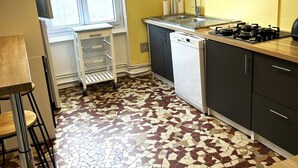 A kitchen with a tiled floor, a sink, a dishwasher, and a stove. - Apartment in Moulins: Comfort with Balcony, Linens and Towels Included (Moulins)
