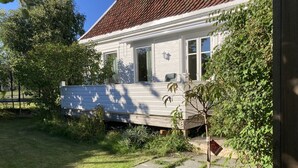 A house with a white exterior, a red-tiled roof, and a front porch.