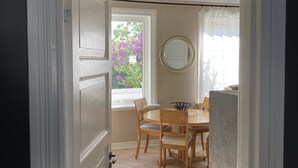 An open door leading to a dining area with a round table and wooden chairs.
