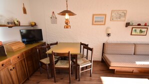 Un coin repas avec une table et des chaises en bois, un téléviseur et un canapé.