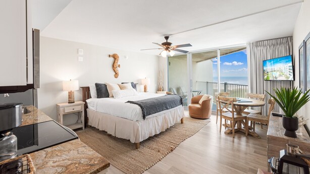 Une chambre d’hôtel moderne dotée d’un grand lit, d’un coin repas, d’une cuisine et d’un balcon avec vue.