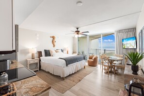 Et moderne hotelværelse med en stor seng, et spiseområde, et køkken og en balkon med udsigt.