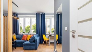 A modern living room with a blue sofa, yellow chairs, and a wooden floor. - Comfortable Studio | Workspace | Close to the Marketplace (Kraków)