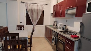 Une cuisine compacte avec un coin repas, comprenant une table et des chaises, un lave-linge, une cuisinière et un réfrigérateur.
