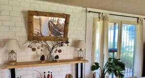 Cozy retreat with a rustic charm, featuring a brick wall, wooden shelf, and a large window with curtains.