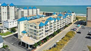 A beachfront hotel with multiple buildings, a parking lot, and a view of the ocean. - Beautiful 3 Bedroom, 3 Bath Oceanblock Condo Mid-Town with Indoor Pool (Ocean City)