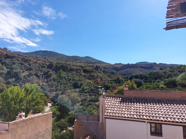 A hillside view with a building featuring a tiled roof and a small window.