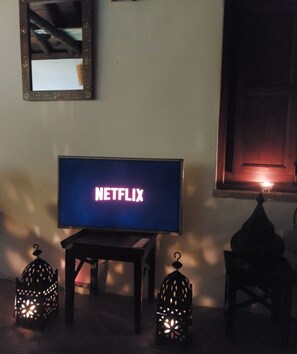 A television displaying the Netflix logo, a mirror, and two decorative lanterns in a dimly lit room. - Casa Balcón- Increíbles Vistas! (Saleres)