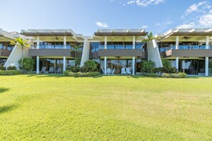 Un hotel moderno con techo plano, varios balcones y un césped bien cuidado.