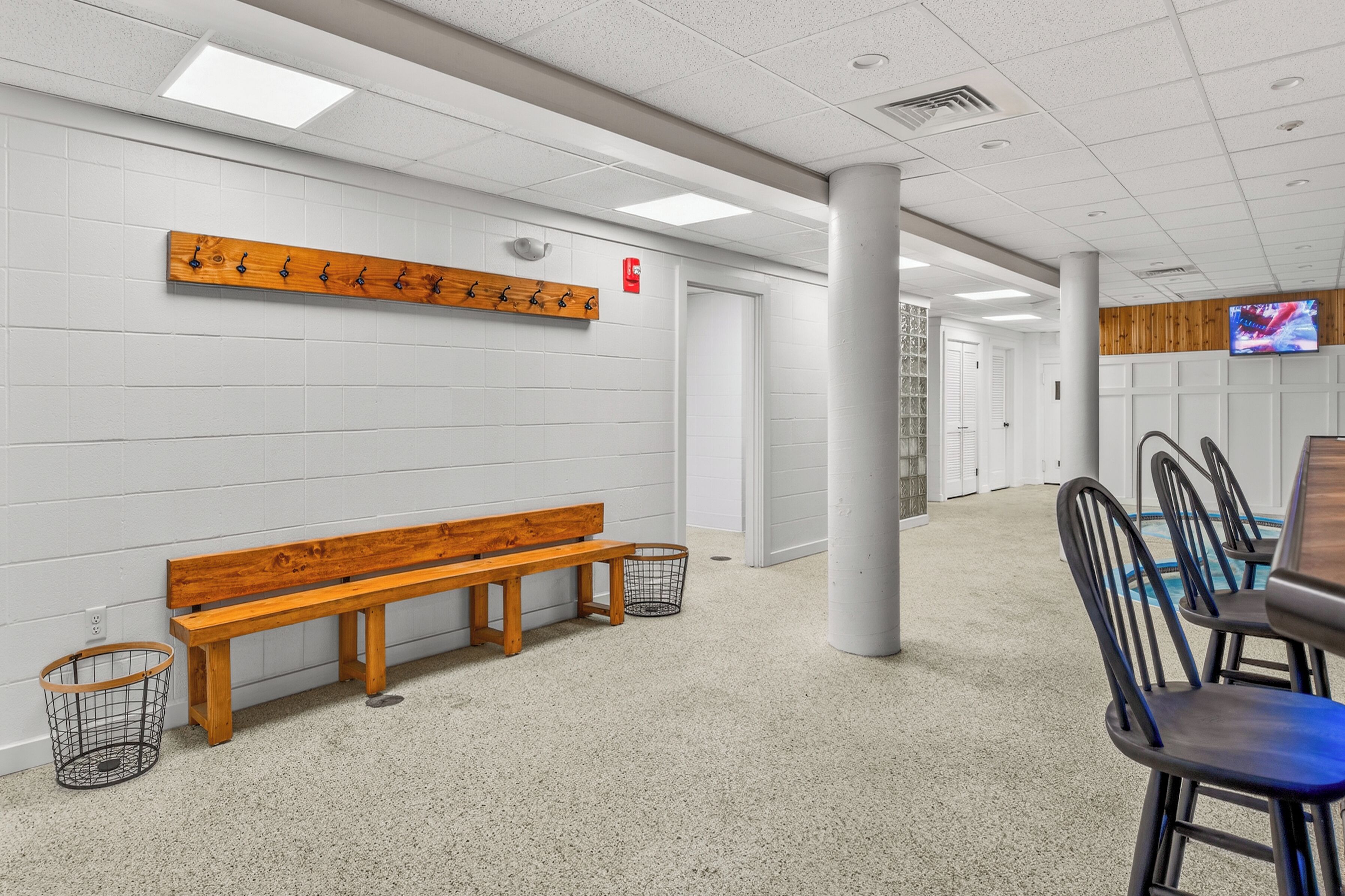 Une salle d’attente propre et moderne, avec un banc en bois, un téléviseur fixé au mur et une rangée de chaises.