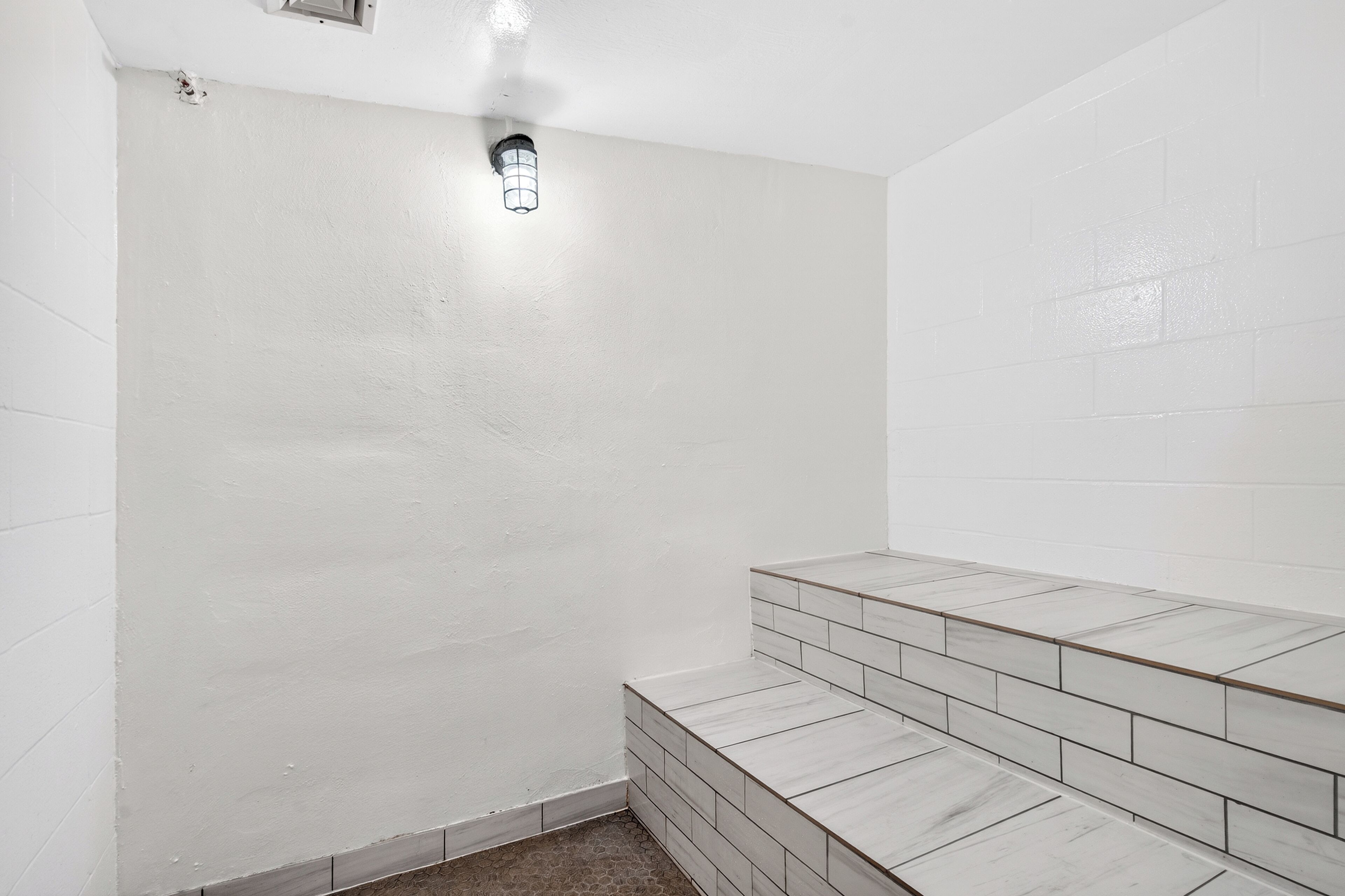 A bathroom with white walls, a tiled floor, and a light fixture.