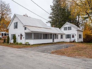 A two-story white house with a porch, a garage, and a small attached building. - Bethel Village Carriage House Apartment (Bethel)