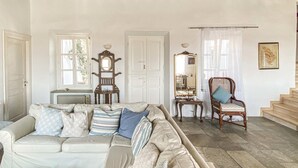 A cozy living room with a beige sofa, a wooden chair, and a mirror. - Gorgeous home in Sifnos (Sifnos)