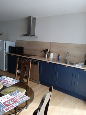 Een moderne keuken met een magnetron, fornuis, spoelbak en houten kastjes.